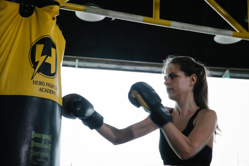 pexels-photo-7991669 Strong fit woman doing boxing punches on bag in gym